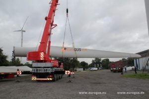 кран загружает лопасти ветряка на длиномерный трал